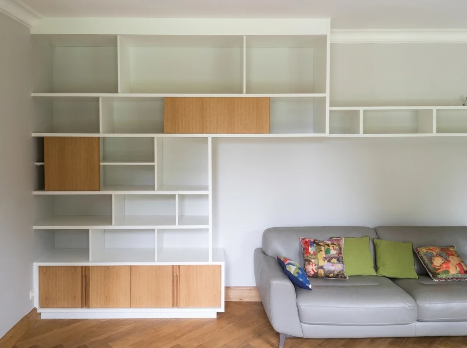 Salon moderne avec bibliothèque murale sur mesure en MDF laqué blanc, intégrant des façades de placards en bois de chêne naturel