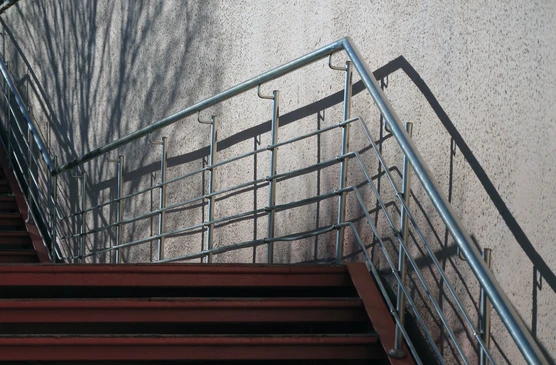 Escalier m&eacute;tallique industriel en acier avec marches antid&eacute;rapantes &agrave; relief diamant, fix&eacute; sur mur en b&eacute;ton brut